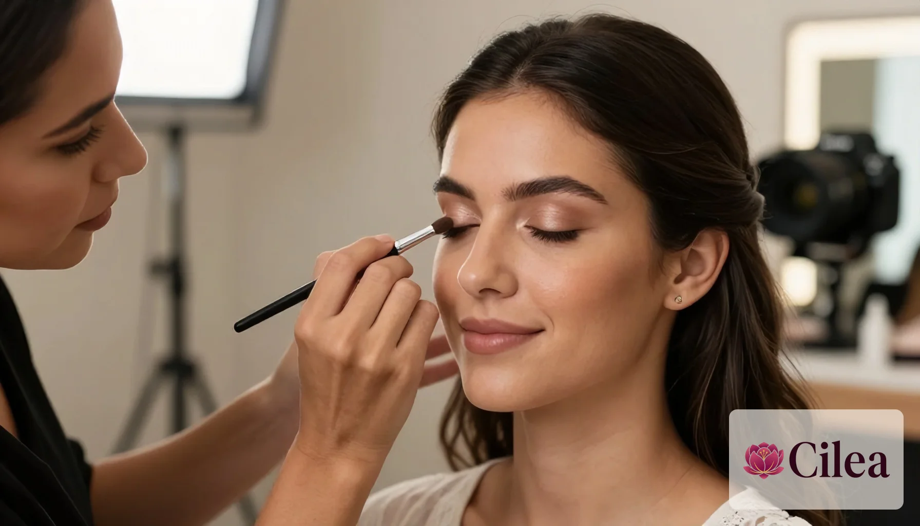 Maquiadora aplicando sombra nos olhos de uma cliente durante produção de maquiagem para noiva